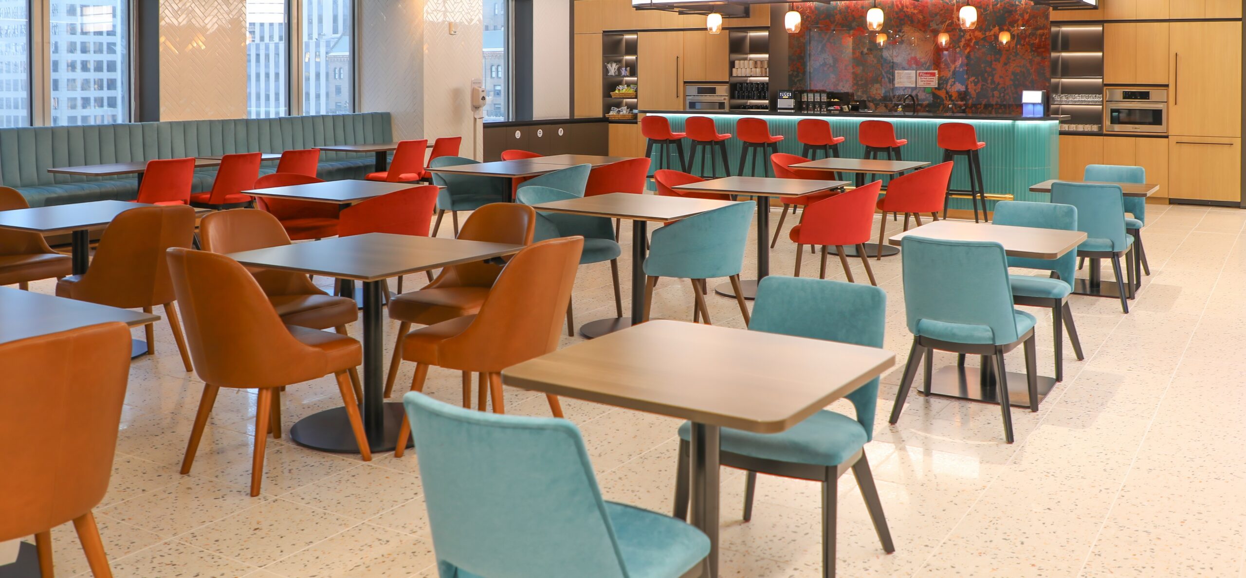 A cafe area with several tables and chairs for employees to use.
