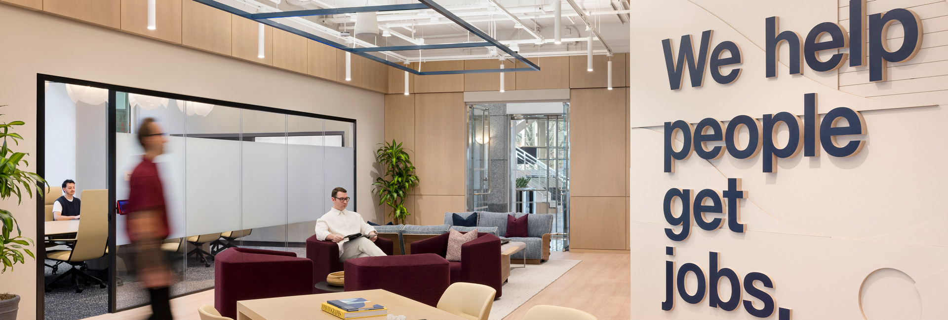 A hallway with a couch next to conference rooms.