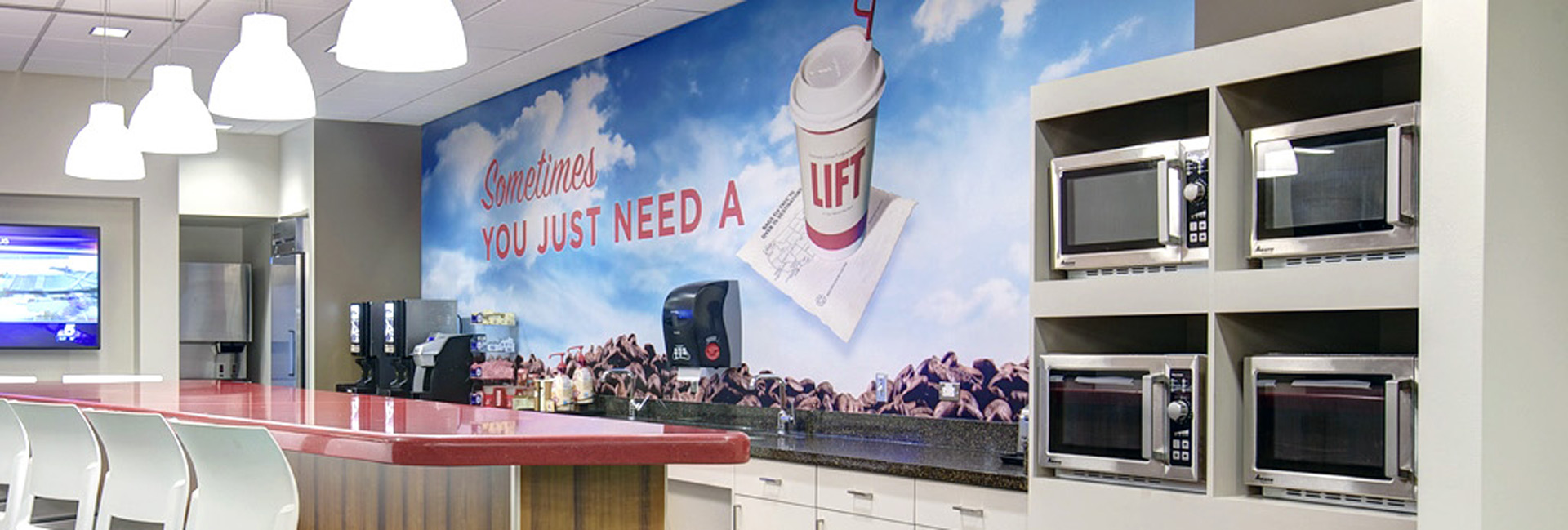 Southwest Airlines headquarters café and break area featuring a communal counter, coffee station, microwaves, and a colorful wall mural with the message, "Sometimes You Just Need a Lift."