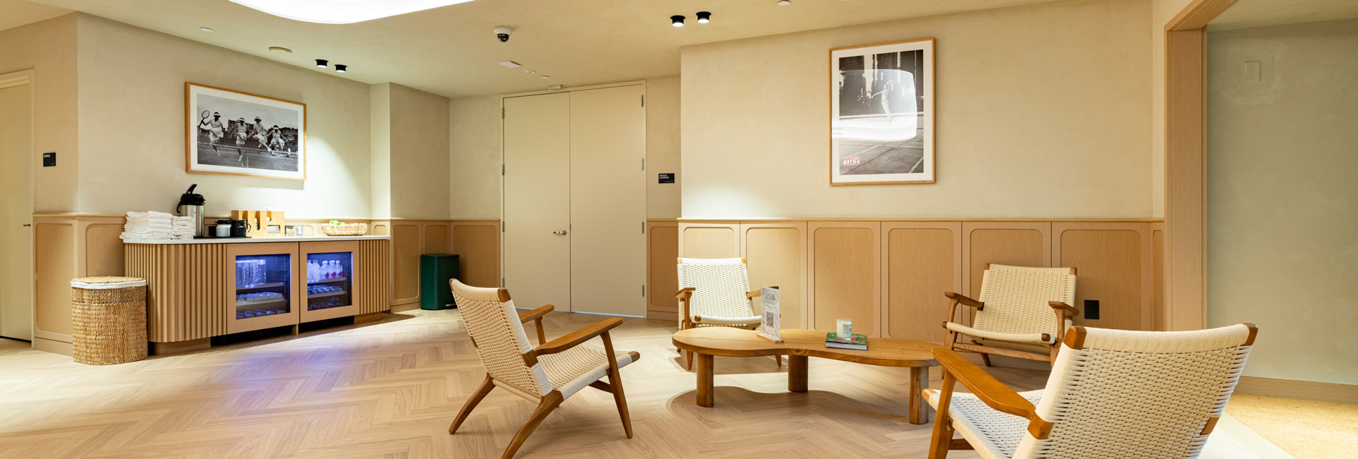 Hospitality lounge with woven chairs, a low wooden table, and a refreshment station.