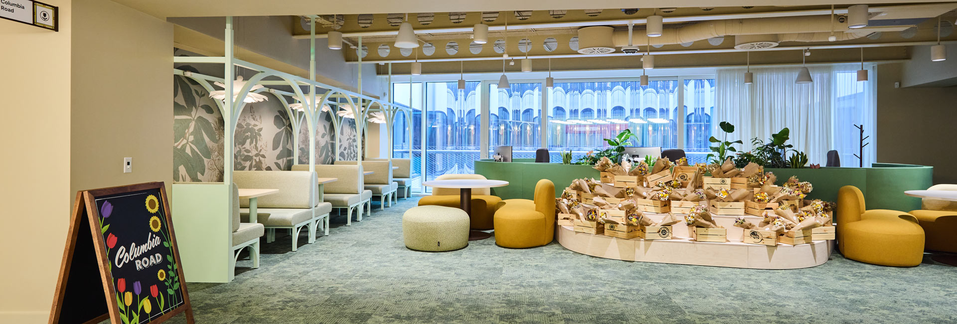 Pinterest’s London office with mint-green booths, mustard lounge chairs, plants and a central floral display in the Columbia Road area.