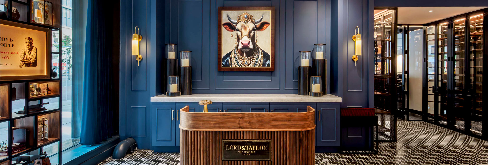 Lord & Taylor Fine Jewelers reception desk against dark blue paneled walls beneath a portrait of a jeweled cow.