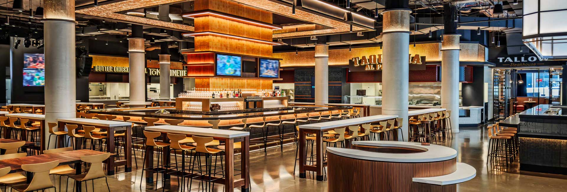 Spacious Shaver Hall dining area with a central bar, communal seating, exposed columns, and multiple food counters.