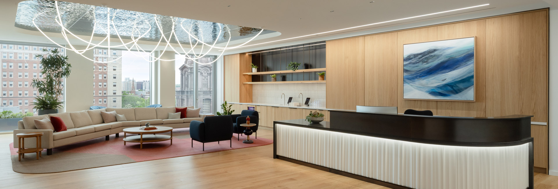 Bain & Company reception area with a curved illuminated desk, modern lounge seating, wood paneling, and sculptural lighting.
