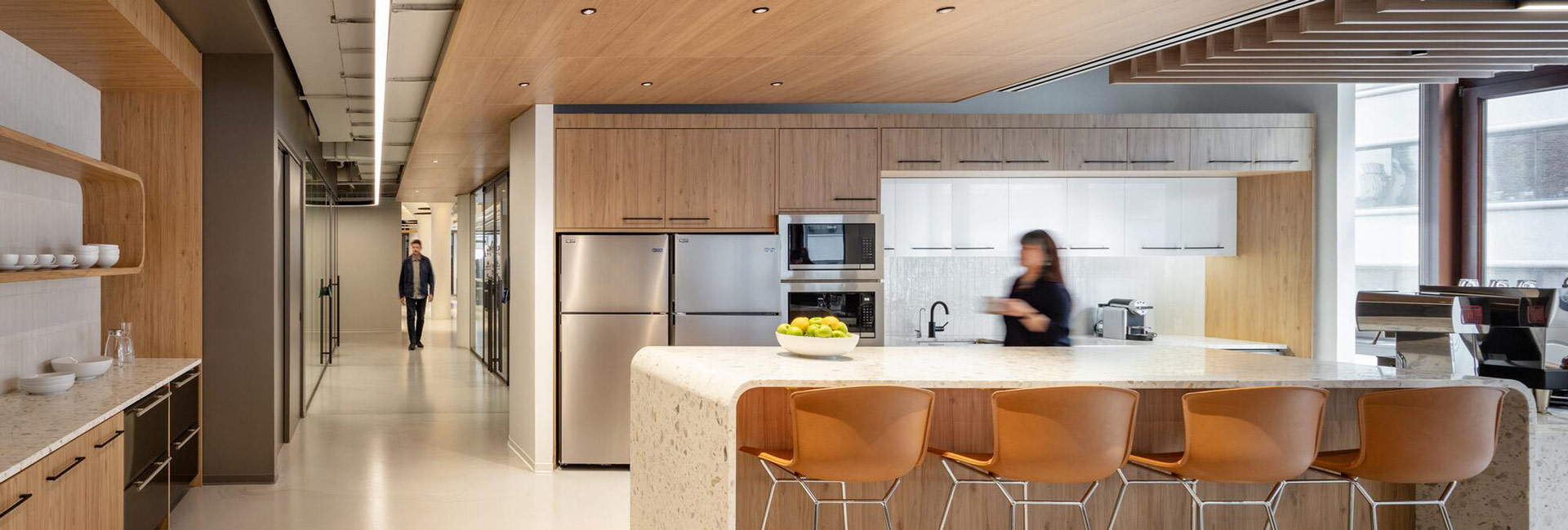 Modern office café with wood cabinetry, stainless steel appliances, a stone island, and counter seating.