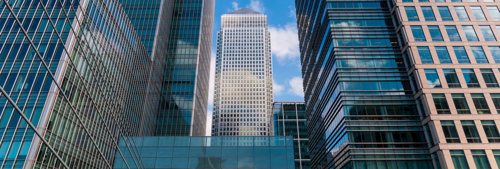 City Skyline Modern glass-and-steel office towers rise against a bright blue sky in a dense urban business district.