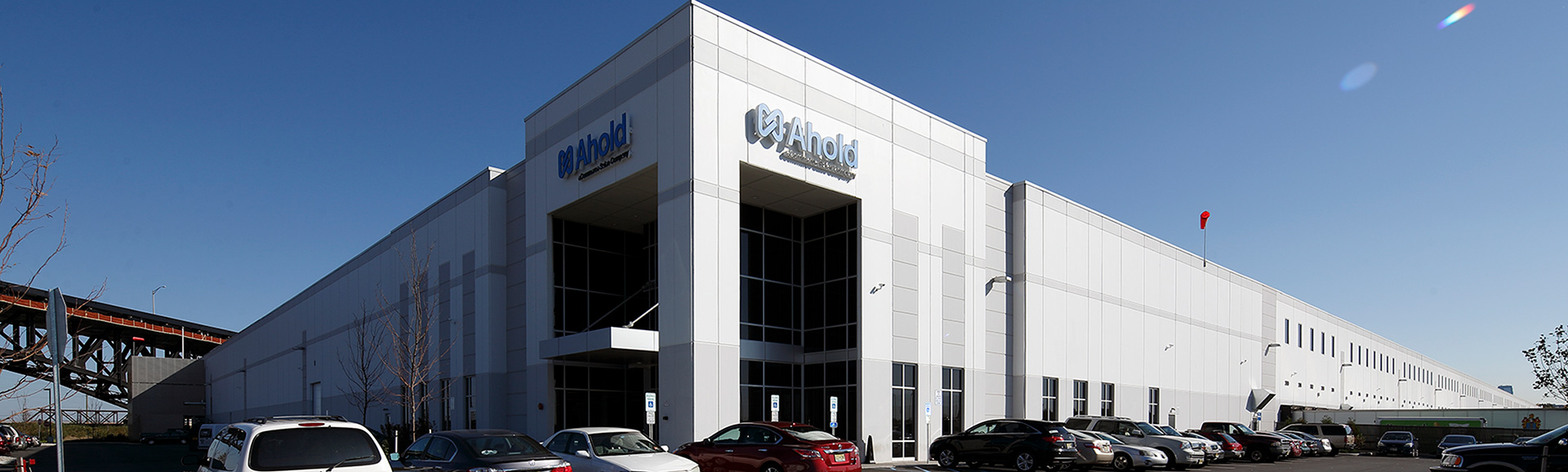 Large white warehouse with multiple cars parked outside.